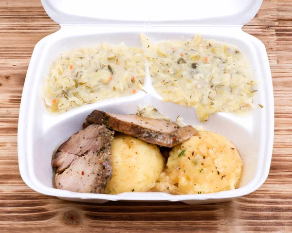 Traditional polish dinner: pork roast and  mashed potatoes topped with gravy, stewed cabbage on the side in biodegradable takeout box