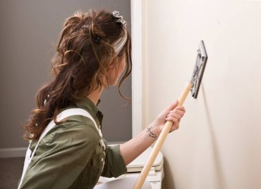 Genç kadın duvar boyama önce kutup sander ile içinde ev remodeling altında zımpara