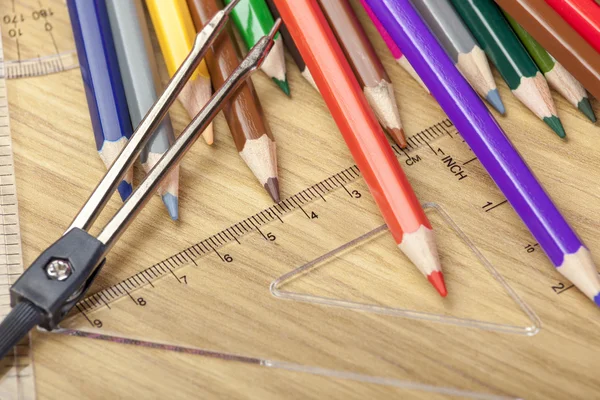Coloring pencils on a desk with a set square — Stock Photo, Image