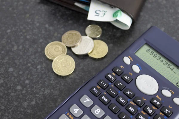 Calculadora em uma mesa preta com uma carteira e alguns trocos soltos — Fotografia de Stock