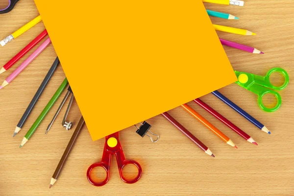 Orange card laying on colouring pencils and scissors — Stock Photo, Image