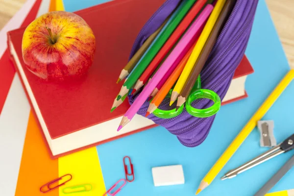 Pencil case and an apple on top of a red book