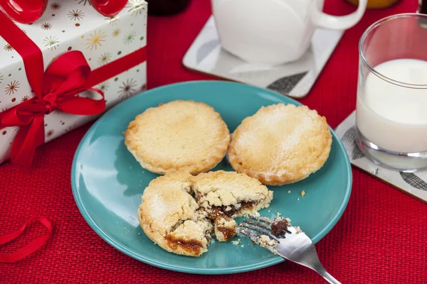 Pasteles de carne picada y un vaso de leche en una mesa roja de Navidad — Foto de Stock