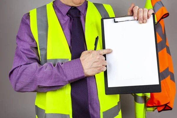 Health and safety instructor in hi viz pointing at a clipboard — Stock Photo, Image