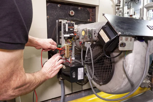 Industrial boiler engineer using a tester to check wiring