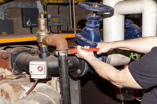 Boiler engineer removing a pipe from a safety valve ストック画像