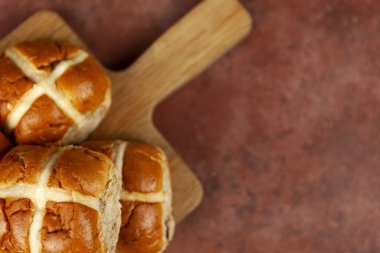Freshly baked hot cross buns on a chopping board