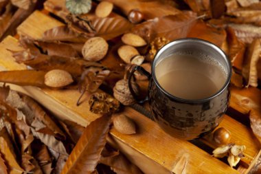 Bir kupa kahve. Sonbahar yaprakları ve fındıklar.