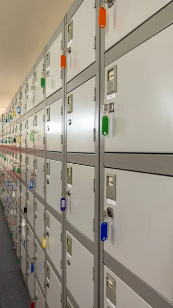 Row of small industrial personal lockers with their keys hanging