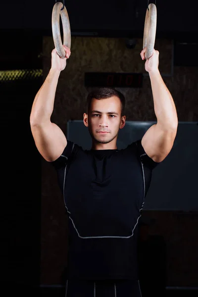 Portret van fit gespierde jongeman met gymnastiek ringen. — Stockfoto