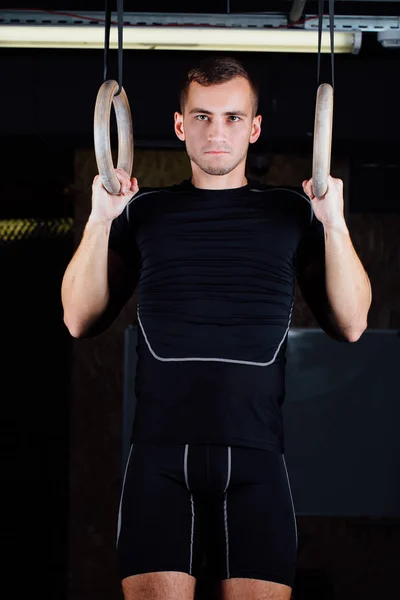 Portret van fit gespierde jongeman met gymnastiek ringen. — Stockfoto