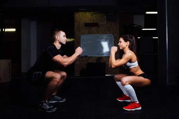 Jovem sorridente e personal trainer exercitam-se no ginásio . — Fotografia de Stock