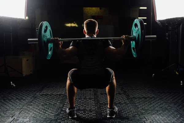 Hombre entrenando sentadillas con barras sobre la cabeza . — Foto de Stock