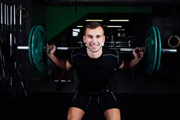 Hombre entrenando sentadillas con barras sobre la cabeza . — Foto de Stock