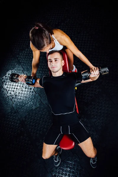 Kobiece osobistego instruktora fitness pomaga młodym mężczyzną o siłowni. — Zdjęcie stockowe