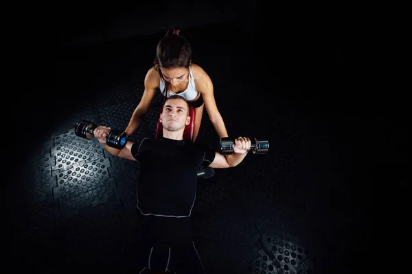 Spor salonunda genç bir adam yardımcı kadın kişisel fitness eğitmeni. — Stok fotoğraf