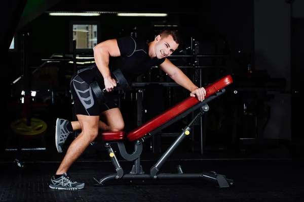 Atletisk man tyngdlyftning på gymmet på bänken med hantel. — Stockfoto