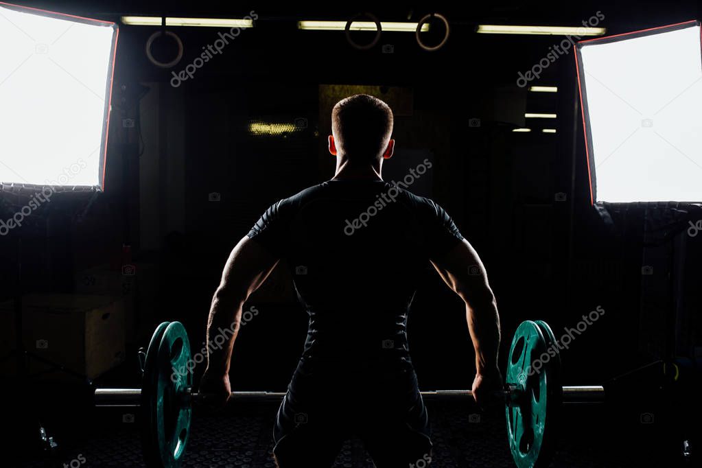 Man training squats with barbells over head.