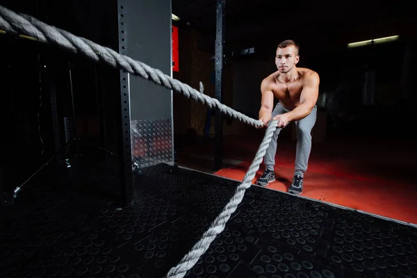 Men with battle rope in functional training fitness gym