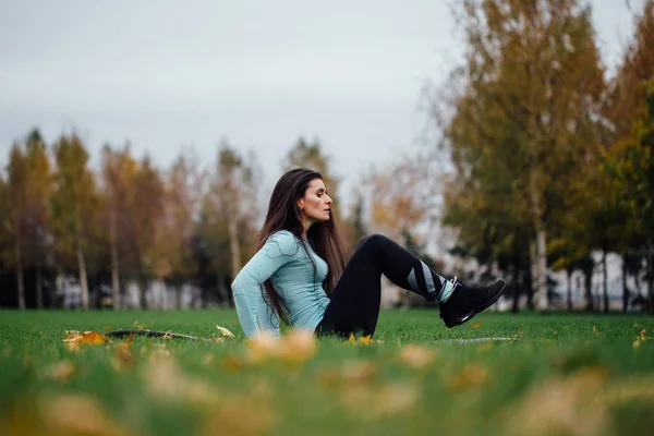 Beautiful girl does exercises with press at the grass — Stock Photo, Image