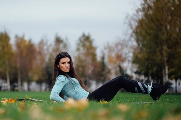 Beautiful girl does exercises with press at the grass — Stock Photo, Image