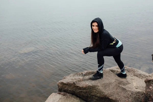 Young fit woman stand on rocks and rest after a hard workout. — Stock Photo, Image