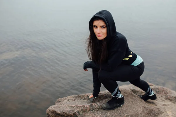 Jonge vrouw stand op rotsen past en rusten na een zware training. — Stockfoto