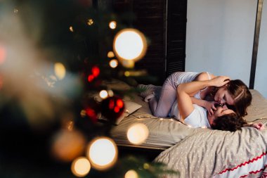 Yatakta dinleniyor çift Noel ağacı yakınındaki