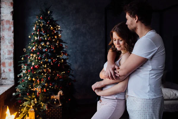 Ζευγάρι στο πιτζάμες σε χριστουγεννιάτικο δέντρο φόντο — Φωτογραφία Αρχείου