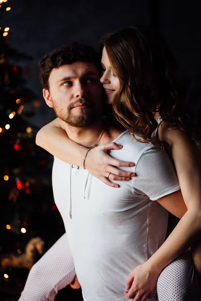 Pareja en pijama sobre fondo de árbol de Navidad —  Fotos de Stock