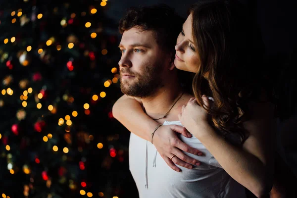 Paar in pyjama op kerstboom achtergrond — Stockfoto