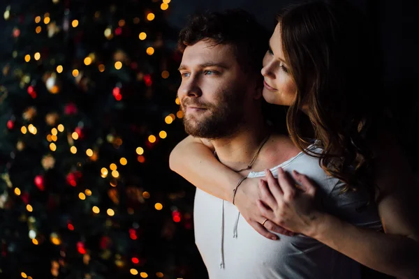 Casal em pijama no fundo da árvore de Natal — Fotografia de Stock