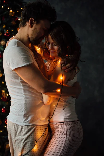 Pareja en pijama sobre fondo de árbol de Navidad —  Fotos de Stock