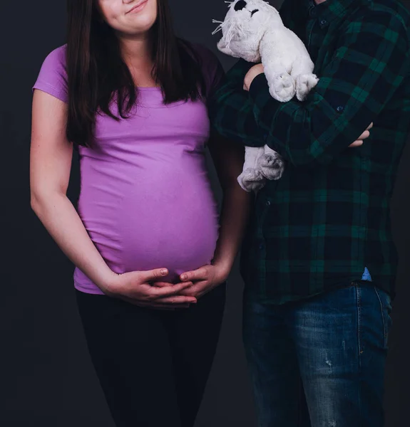 Unga gravida par väntar. i studion på en mörk grå ba — Stockfoto