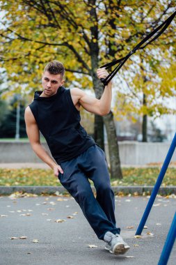 Trx eğitim. Adam eğitmen parkta Excersise yapıyor. Fitness Egzersiz.