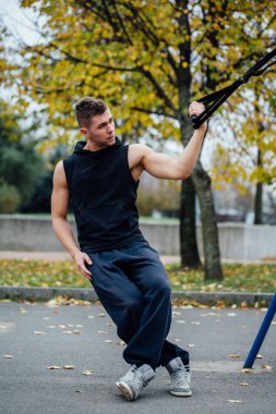 Trx eğitim. Adam eğitmen parkta Excersise yapıyor. Fitness Egzersiz.