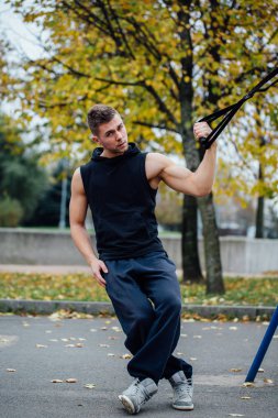 Trx eğitim. Adam eğitmen parkta Excersise yapıyor. Fitness Egzersiz.