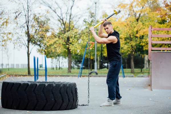 Fitness Sport Mann Workout im Freien. mit Hammer und Traktorreifen. — Stockfoto