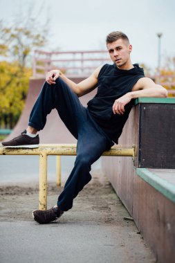 Yakışıklı delikanlı bir kaykay parkı rampa üzerinde dinlenme.