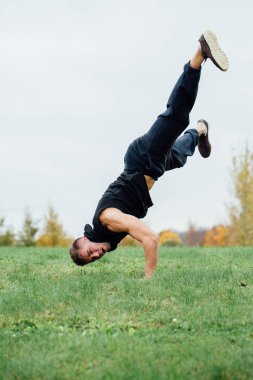 yeşil bir tepede eller üstünde ayakta sağlıklı spor adam. Bitmemiş bir bina zemine karşı. zor egzersiz.