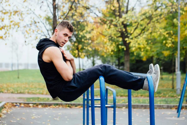 Hombre de fitness haciendo ejercicios estomacales en la barra horizontal al aire libre —  Fotos de Stock