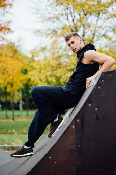 Portret van een man zelfverzekerd fitness. Man vormt op skate-helling, tegen de achtergrond van de herfst bos. Val. — Stockfoto