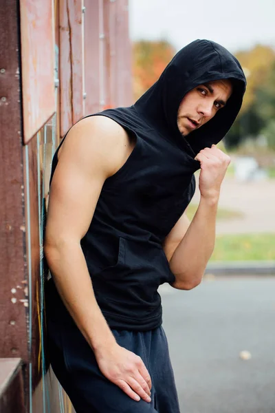 Retrato de um homem bonito forte em pano de treino. Posando no capô . — Fotografia de Stock