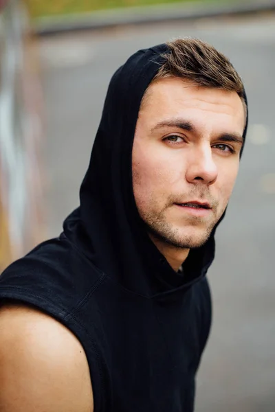 Retrato de un hombre fuerte y guapo en tela de entrenamiento. Posando en el capó . —  Fotos de Stock