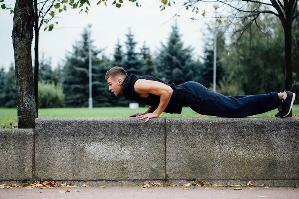 男跑步锻炼，在秋天公园锻炼。俯卧撑与板凳. — 图库照片