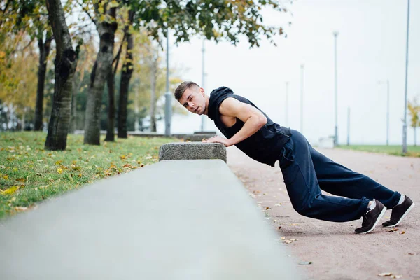 남성 러너 운동가 공원에 운동 하 고. 벤치와 함께 팔 굽 혀 펴기. — 스톡 사진