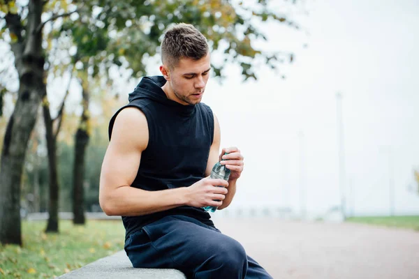 Atleet rusten Eritreërs na draait met fles water. Rust een zware training. — Stockfoto