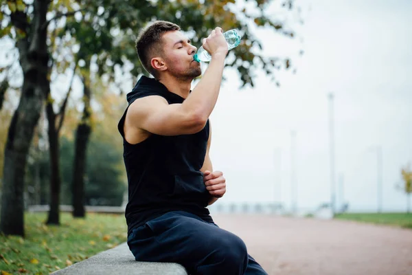 Atleet rusten Eritreërs na draait met fles water. Rust een zware training. — Stockfoto