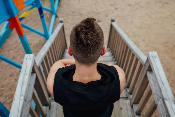 Back view of young sport man with strong calves muscle posing outdoors in playground. — Stock Photo, Image