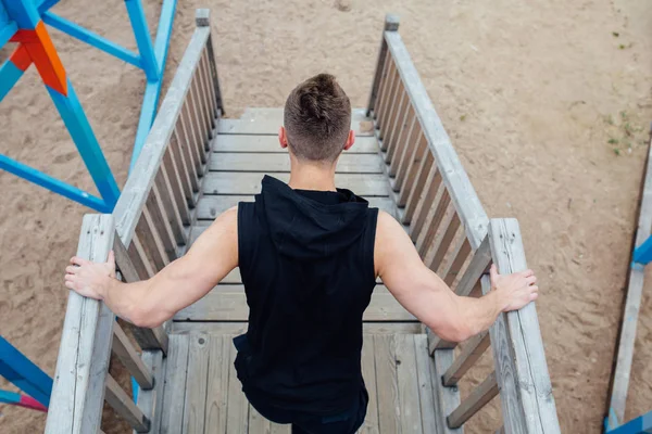 Back view of young sport man with strong calves muscle posing outdoors in playground. — Stock Photo, Image